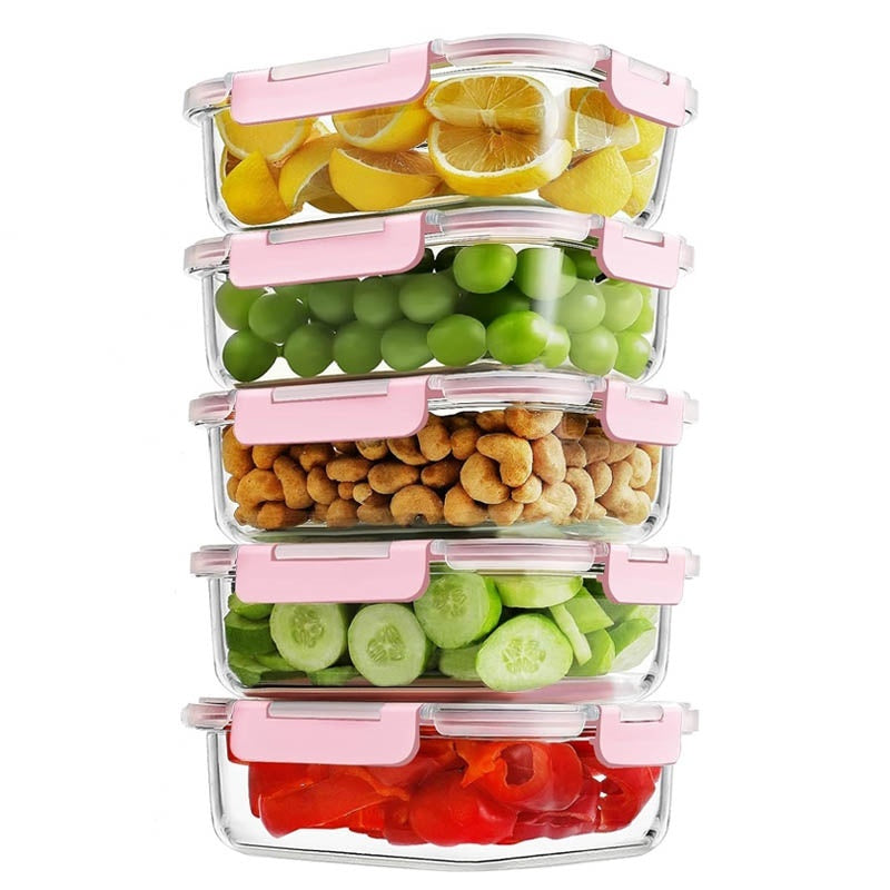Five stacked glass food containers with pink lid clips holding lemon slices, grapes, cashews, cucumber slices, and red pepper pieces.